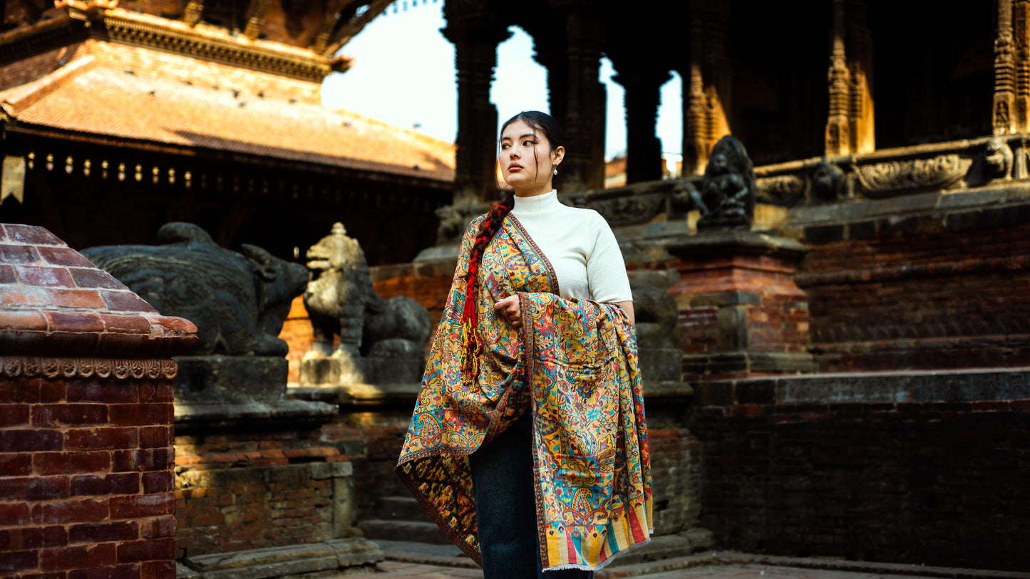 Woman in a colorful coat standing in front of ancient stone architecture